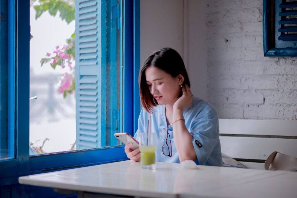 A person browsing profiles thoughtfully on a smartphone at a table indoors