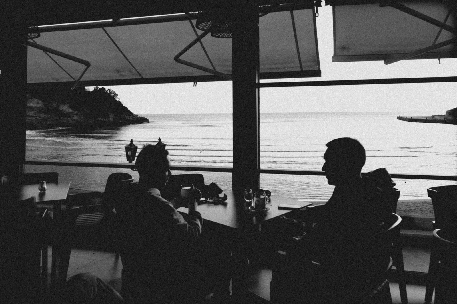 Two adults in relaxed conversation at an outdoor table in the late afternoon