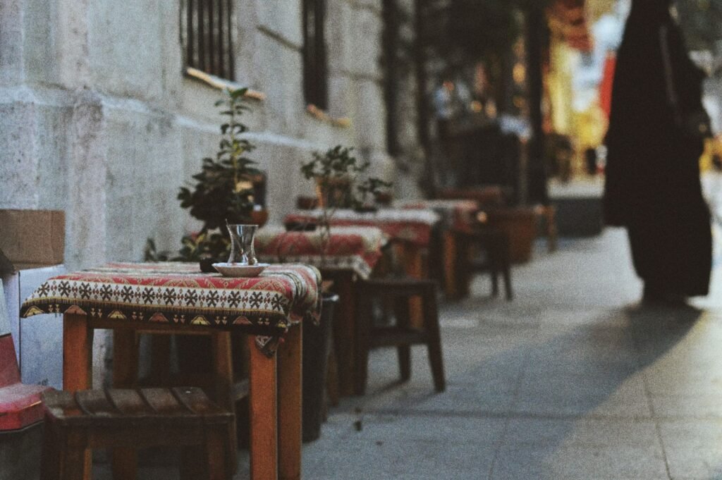 Outdoor cafe tables in a Nigerian town at dusk with people talking