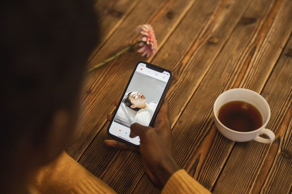 Person holding a smartphone showing a messaging app beside a cup of tea