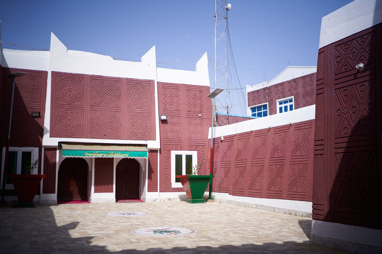 Quiet guesthouse courtyard in northern Nigeria at golden hour with an empty bench