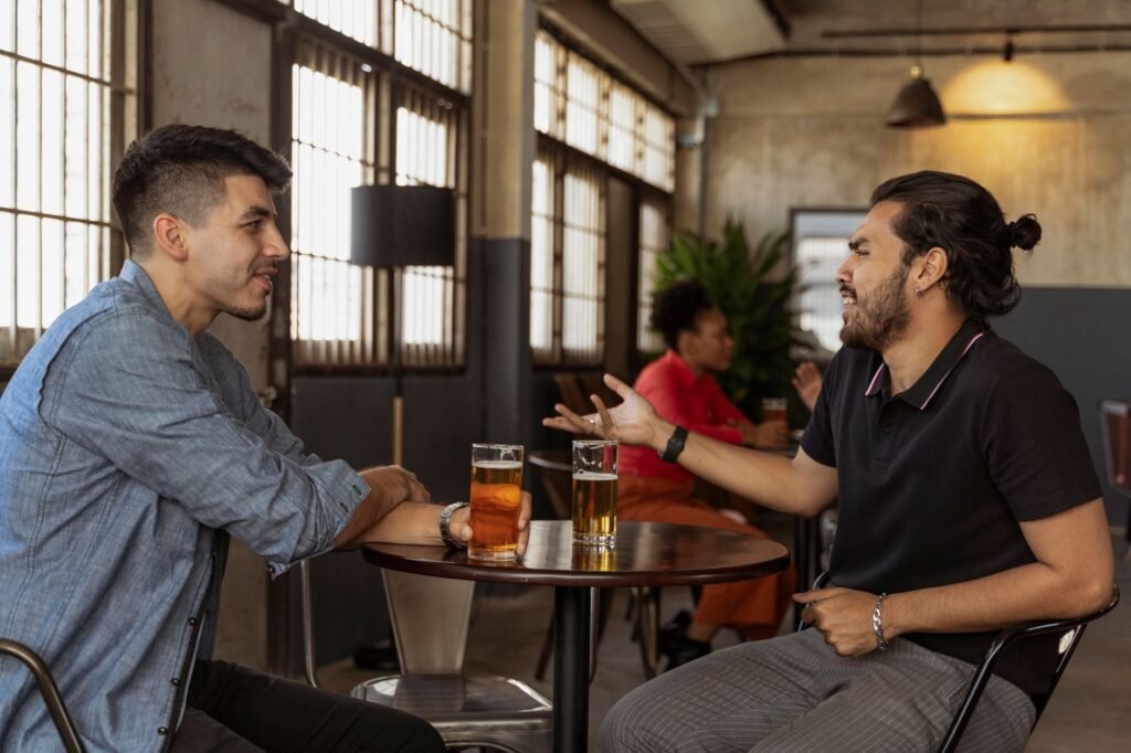Two adults in relaxed conversation at a small table in a modest Nigerian eatery