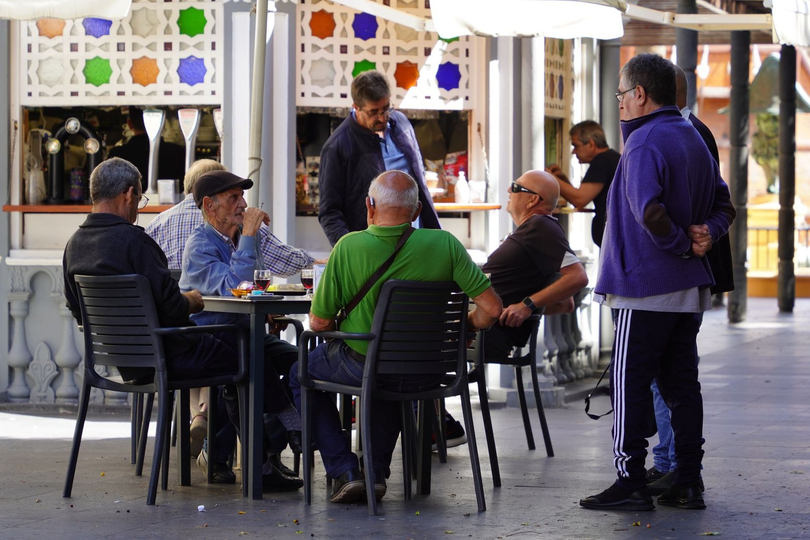 Two adults in relaxed conversation at an outdoor table in a quiet town