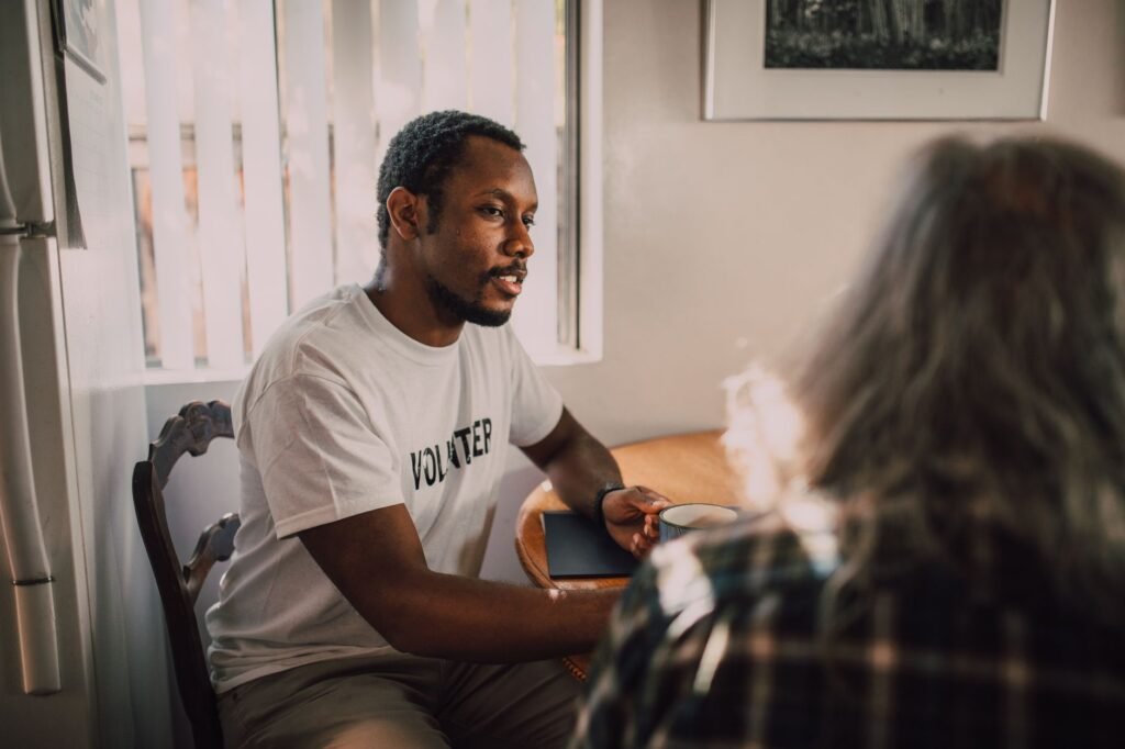 Two adults in calm conversation across a small table in a softly lit room