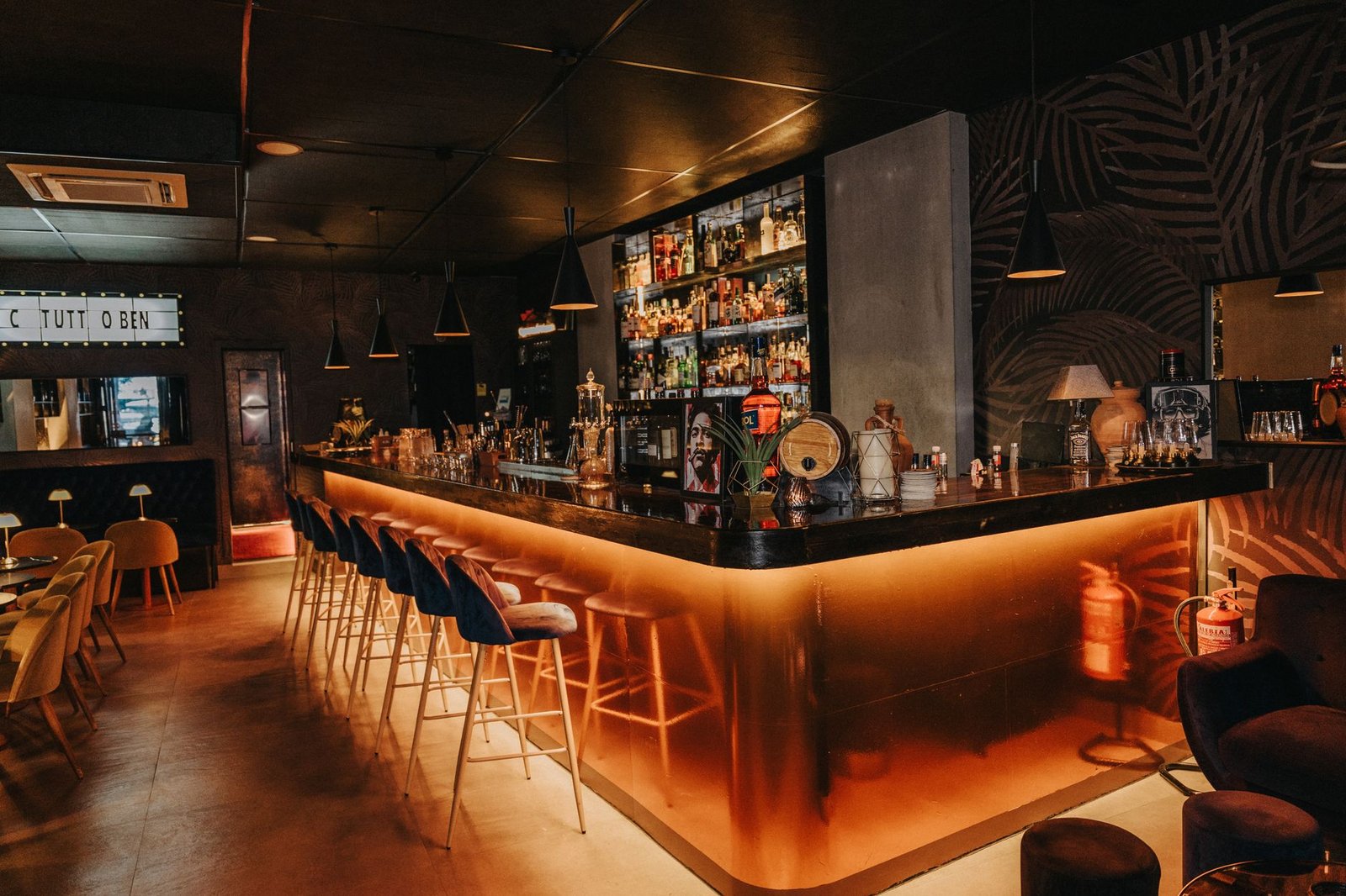 A softly lit lounge interior at dusk with seated adult patrons in smart-casual dress