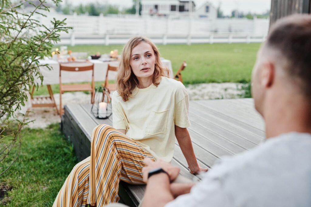 Two adults in quiet conversation at an outdoor table in the evening