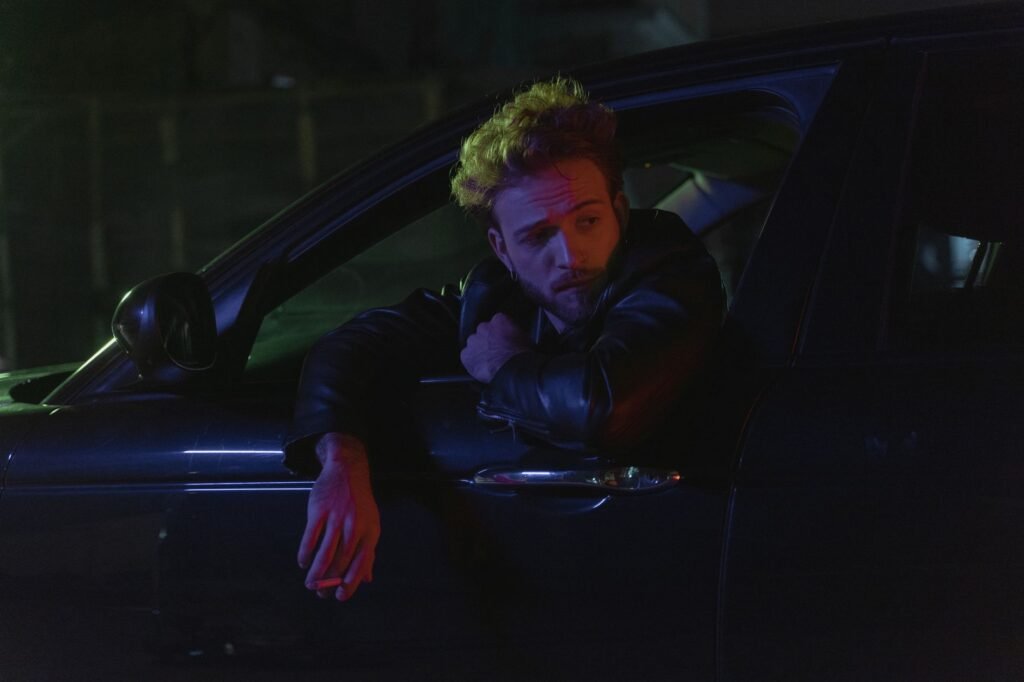 Car parked on a town road at night with a driver waiting nearby