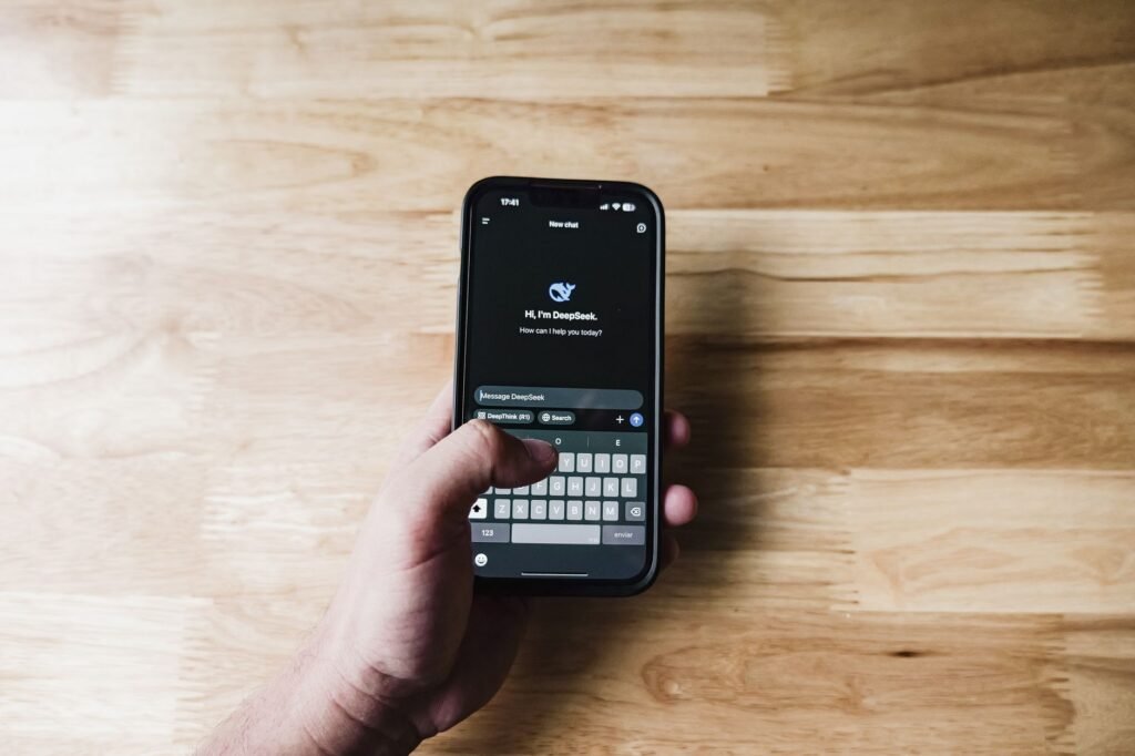 Person typing a polite message on a smartphone beside a notebook