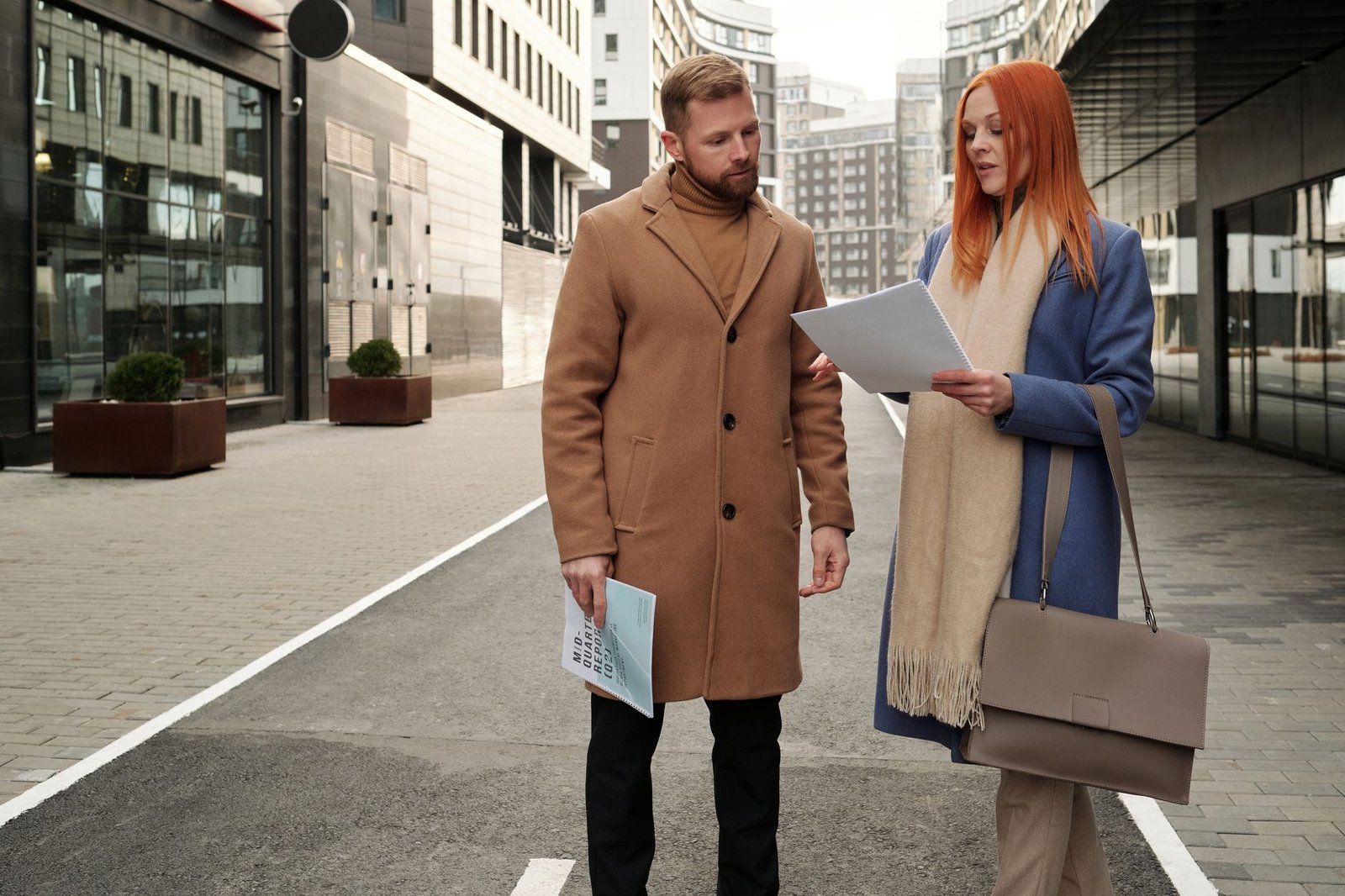 Two adults greeting each other politely at an outdoor table in a quiet town setting