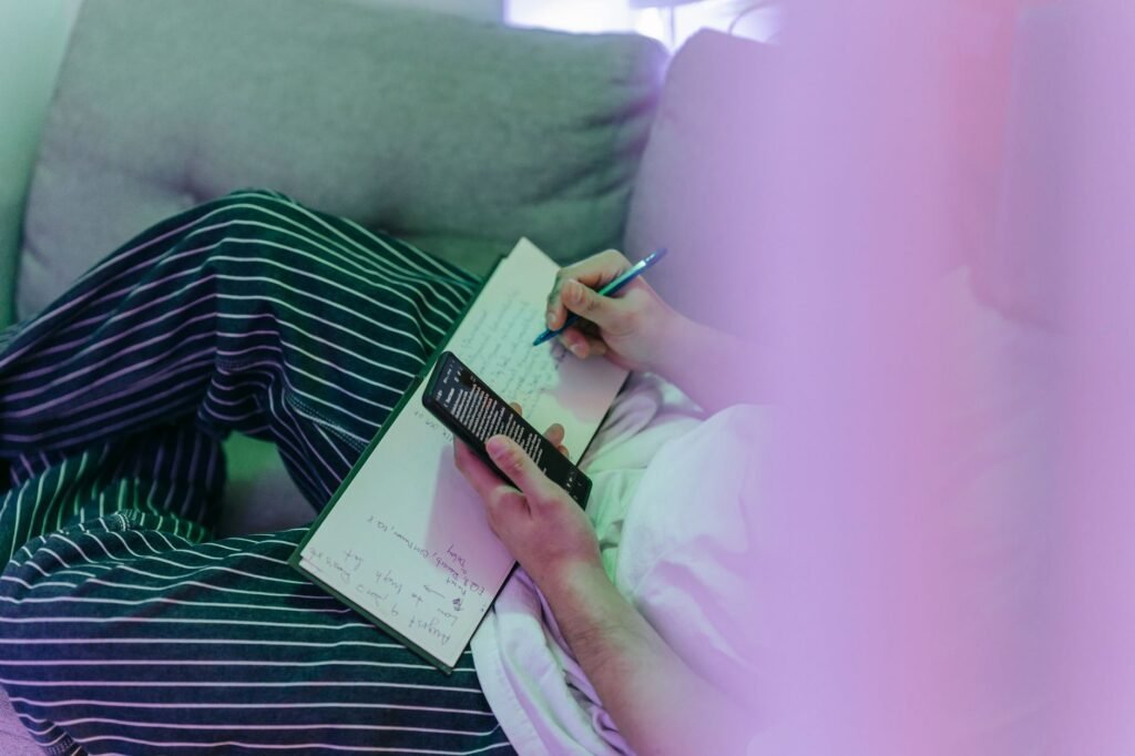A person planning a booking with a smartphone and notebook in a calm indoor setting