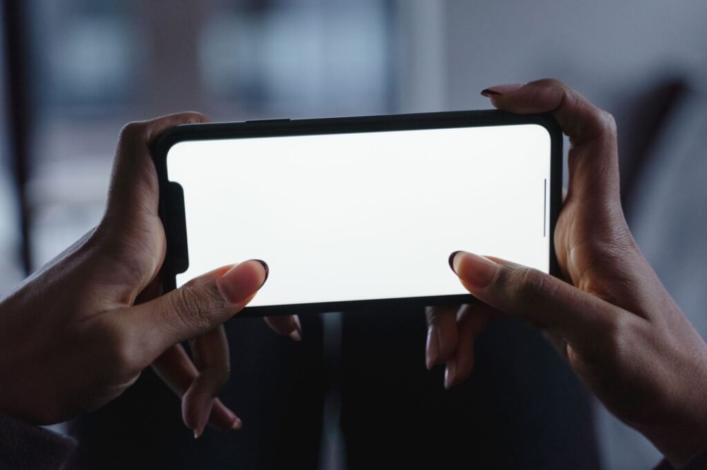 Hands holding a smartphone while browsing a listing, with a notebook on the table