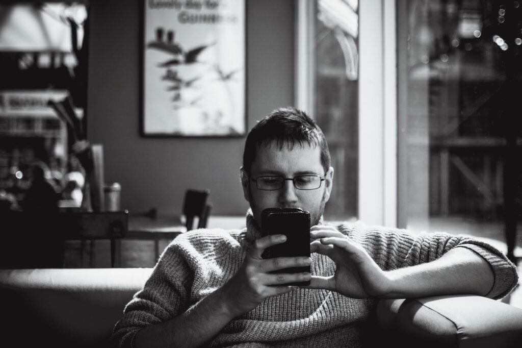 Man sitting indoors looking thoughtfully at his smartphone