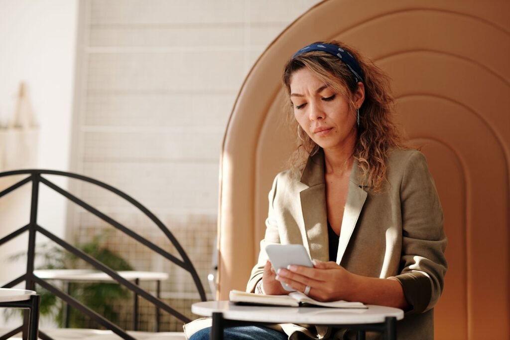 Adult checking a smartphone at a table in a modest room in daylight