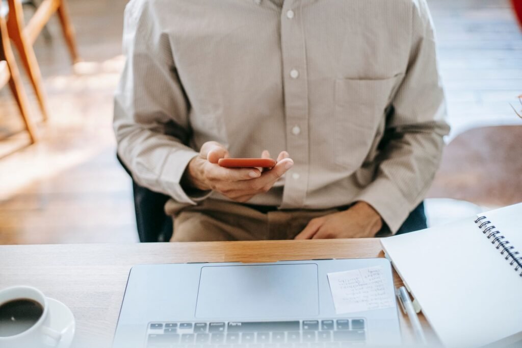 Person typing a respectful message on a smartphone beside a notebook